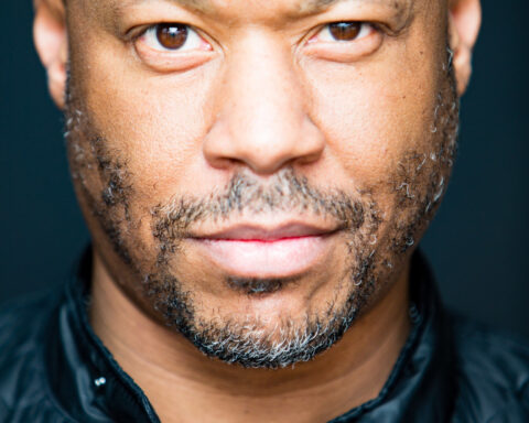 Ritratto fotografico in primo piano del produttore techno Robert Hood con giacca nera su sfondo scuro